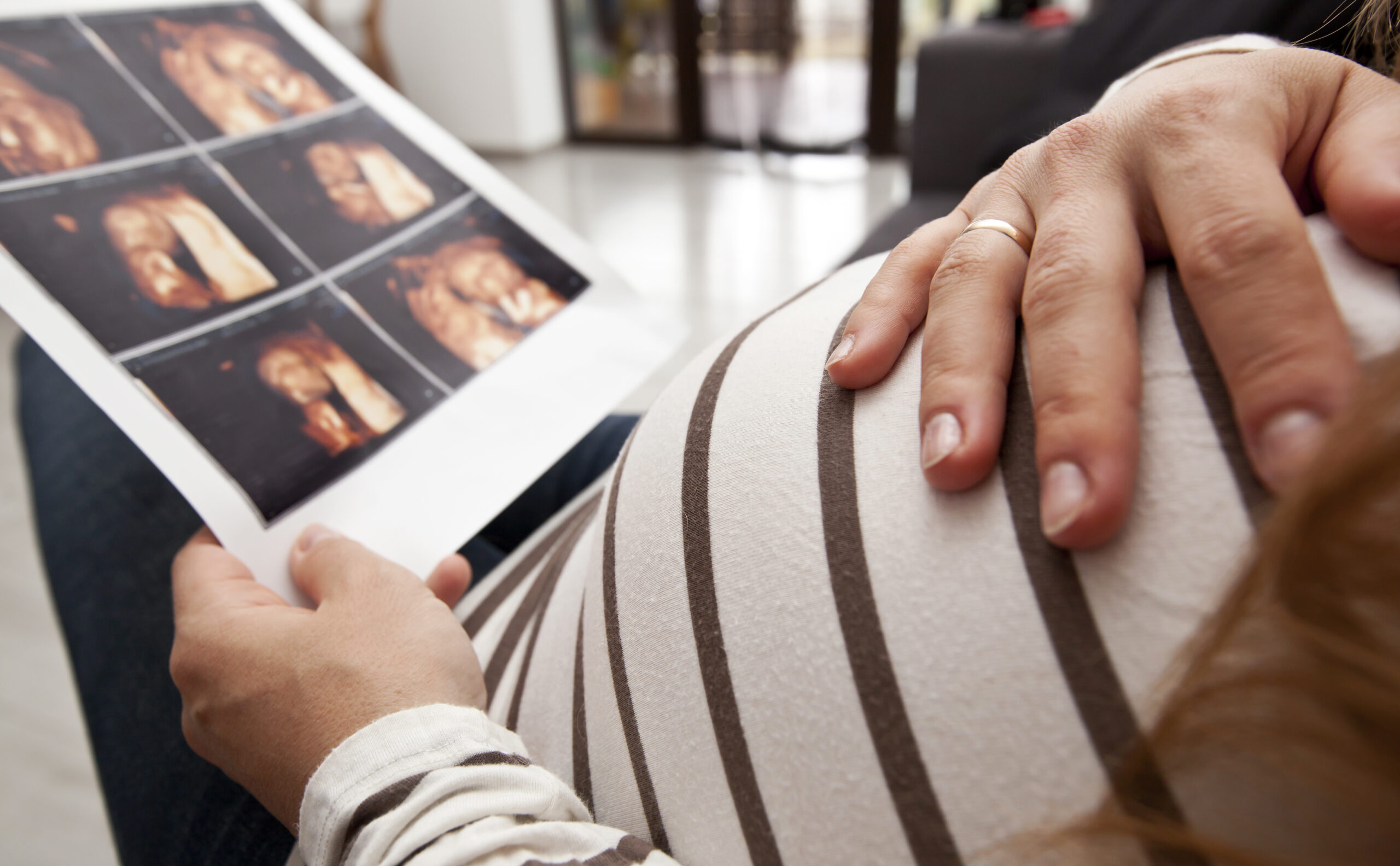 The pregnant woman is looking on the photo of her child making b